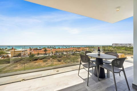 Modern balcony offers sweeping views of nearby landmarks, palm-lined streets, and turquoise coastal waters. A stylish dining table awaits your morning coffee or sunset refreshments.