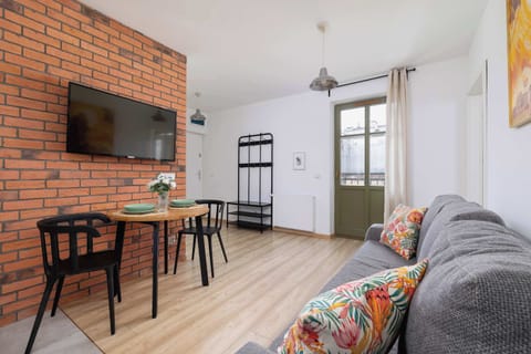 A modern living room with a decorative brick wall, wooden table, and colorful, comfortable sofa creates a stylish and cozy space to relax.