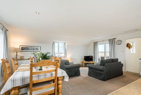 Arnold Cottage in Treyarnon Bay. First-floor open plan living, dining and kitchen area with sofas and sea view window