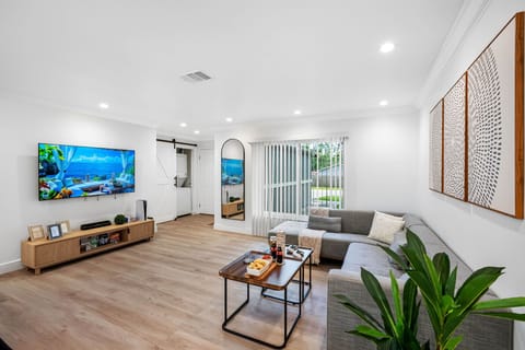 Relax in this sleek and stylish living room, complete with a spacious sectional, mounted smart TV, and calming minimalist décor.