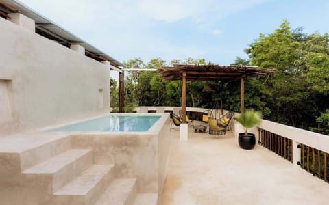 Villa pool terrace with pergola shade, sunloungers, white walls, and lush tropical garden.
