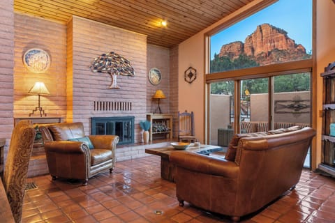 Living room one with dramatic red rock view, natural toned brick, terracotta flooring, large window with sliding door to front porch with seating area.