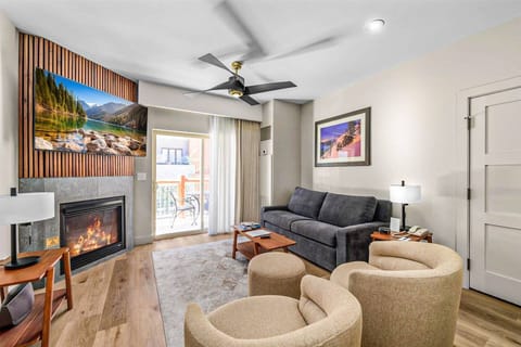 The living room features a custom gas fireplace, comfortable high-end seating, and smart TV. The private patio is located through the glass door.