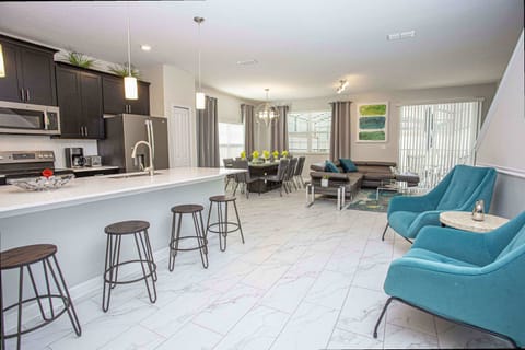 Enjoy seamless living in this bright open-plan space with a roomy kitchen island, stylish dining area for six, plush grey sectional and teal accent chairs - perfect for gatherings!