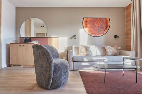 Living area with a grey sofa, armchair, and coffee table — the sofa converts to a double bed for additional guests.