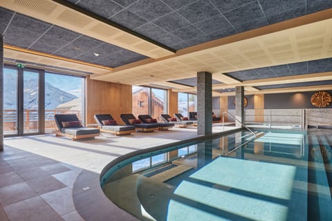 Wide pool deck with loungers and natural light — a calm space to recover after a day on the San Bernardo slopes.