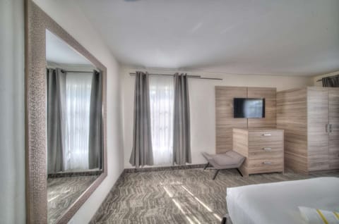 Bedroom with bed, dresser, windows, and carpet flooring