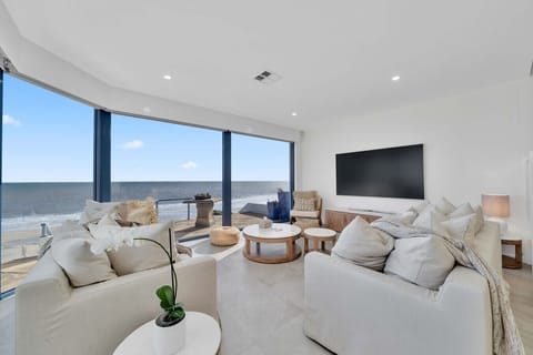 Ground-floor living room with stunning full ocean views, furnished with plush white sofas and a chic coffee table