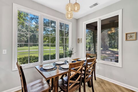 The dining table overlooks scenic views of the greens with seating for all, including additional barstool seating at the kitchen counter.