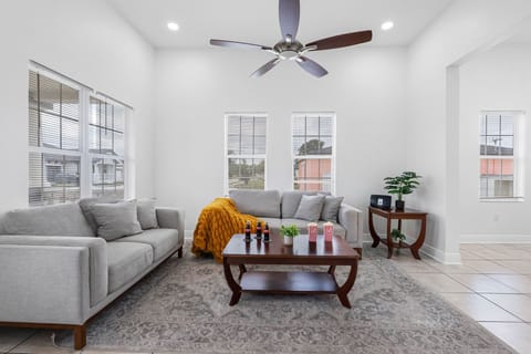 This bright and spacious living room offers comfortable seating, large windows with natural light, and a welcoming layout perfect for relaxing or gathering with family and friends.