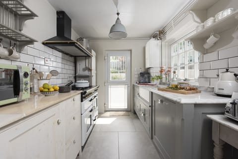 Full kitchen with gas range cooker, microwave and access to outside - Almond Cottage