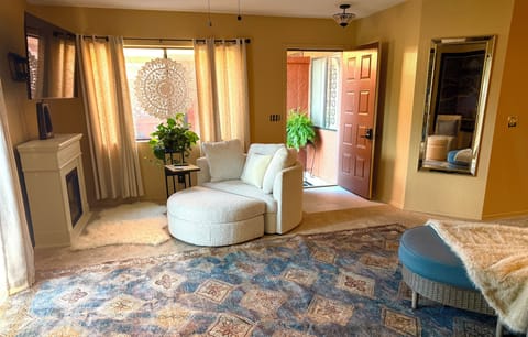 front door of condo and relaxing space near faux fireplace and smart TV