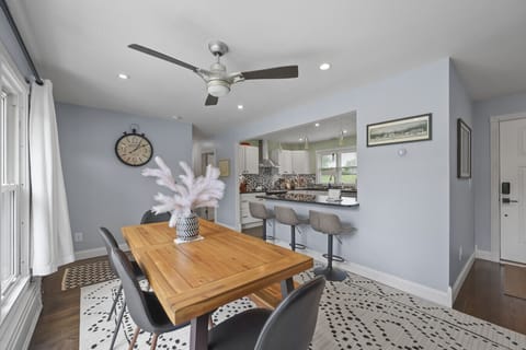 Stylish dining area with wooden table for six, ceiling fan, and open flow to the kitchen.