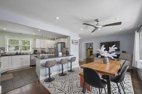 Bright dining space with seating for 6, bar seats for 3, and large windows overlooking greenery.