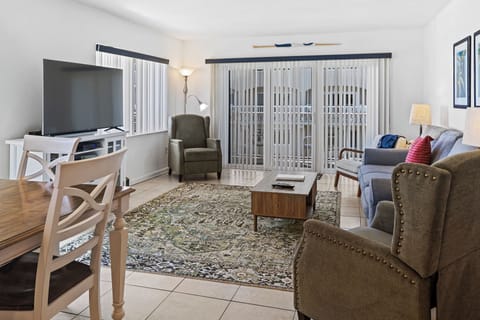 Relax in this inviting beachside living room featuring cozy seating, a large TV, and sliding doors that open to natural light. Perfect for unwinding after a fun day at the ocean.