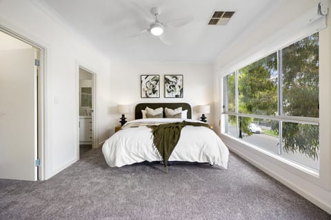 A spacious master bedroom featuring modern furnishings and a calm neutral colour palette.