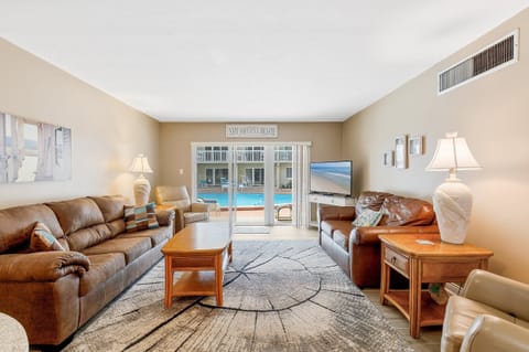 Relax in this spacious poolside living room, perfect for unwinding after beach adventures. Enjoy cozy seating, coastal décor, and easy access to sun and swim just outside your door.