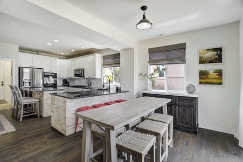 The heart of the home—this open-concept kitchen and dining space features a granite island with bar seating, rustic table for six, and sleek stainless steel appliances throughout.

