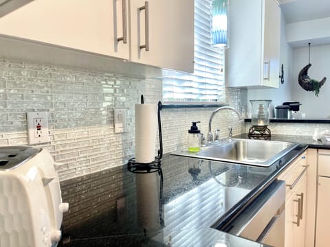 A close-up of the kitchen highlights sleek counters and a sparkling backsplash