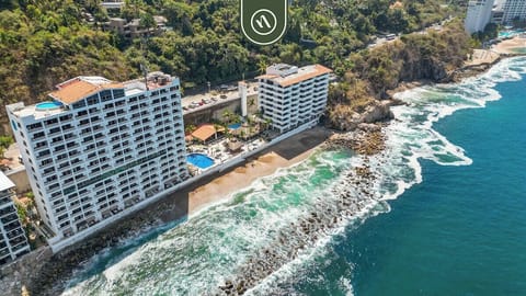 High-angle drone perspective of the coastal building complex nestled along a rocky ocean cove.