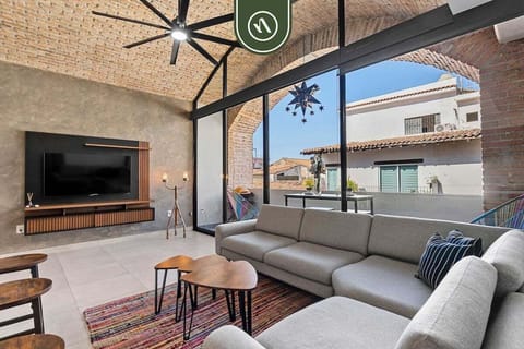 A stylish living area featuring high vaulted brick ceilings, floor-to-ceiling windows, and contemporary furniture.