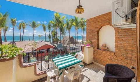Outdoor brick-accented terrace with a small dining set overlooking tropical palm trees and the ocean.