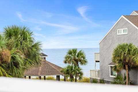 Your beachfront townhome rises from the palms; the Gulf shimmers just past the dunes.