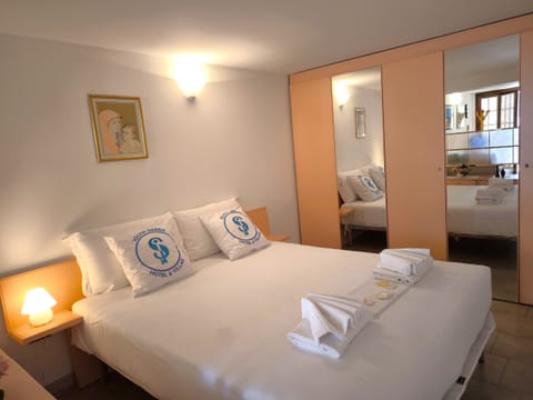 Cozy and well-furnished double bedroom with large mirrored wardrobe and soft lighting. The room, with its attention to detail and warm tones, offers a relaxing atmosphere perfect for resting after a day at Lake Garda.