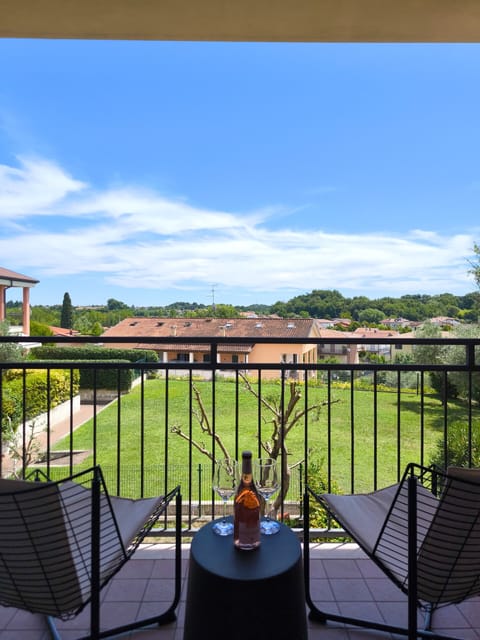 Balcony of the apartment in Peschiera del Garda, furnished with a small table and chairs to enjoy a moment of relaxation with an open view of the communal garden and the rooftops of the area. Ideal for outdoor breakfasts or a glass of wine at sunset.