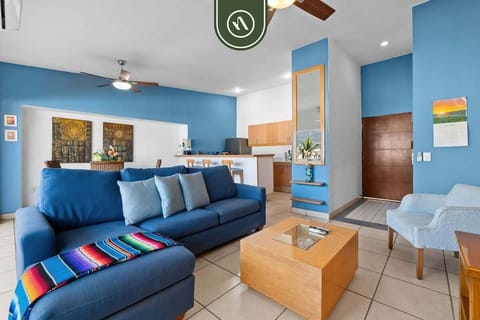 Cozy living area featuring a vibrant blue sectional couch, wooden coffee table, and an accent wall with a built-in shelf.