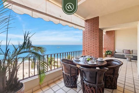 Spacious covered balcony featuring a traditional wooden dining set, brick pillars, and panoramic ocean views.
