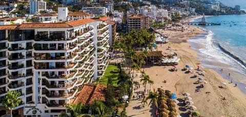 A beautiful high-angle view capturing the multi-story beachfront resort complex and the bustling sandy shoreline.