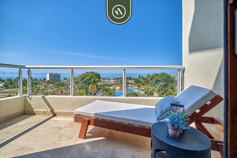 Relax on a premium wooden lounger with a view. This private terrace offers a peaceful spot to soak up the sun while overlooking the lush resort grounds and the ocean beyond.