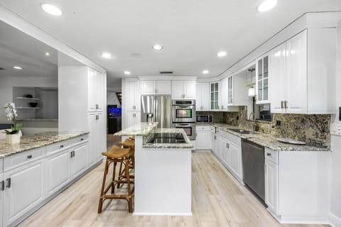 Spacious kitchen with pristine white cabinetry, granite surfaces, and modern appliances