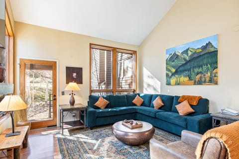 Inviting main living area with a plush sectional, high ceilings and a small patio- the stairs lead down out of the back to the unit.