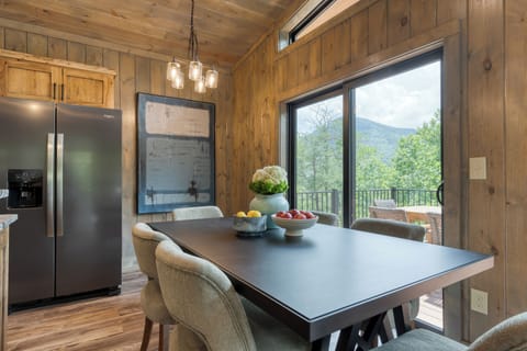 Dining nook with large windows and forest backdrop.