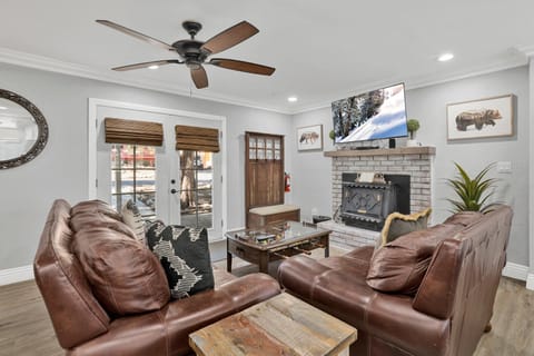 Cozy mountain living room with a stone fireplace, comfy seating, and smart TV—perfect for relaxing evenings, movie nights, and warm cabin vibes after outdoor adventures.