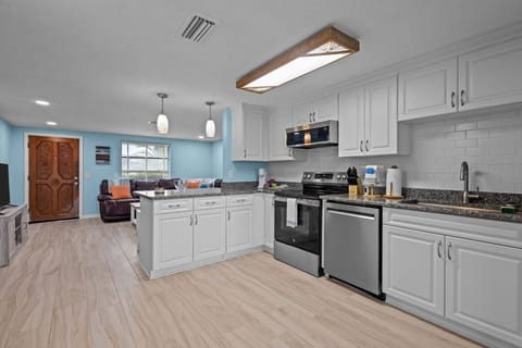 Fully stocked kitchen with stainless steel appliances, white cabinetry, and granite counters—great for home-cooked meals or snacks after the beach.