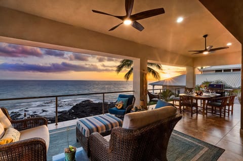Sip sunset mai tais beneath the ceiling fans while the Pacific glitters just beyond the railing—no stairs needed thanks to the home’s private elevator.