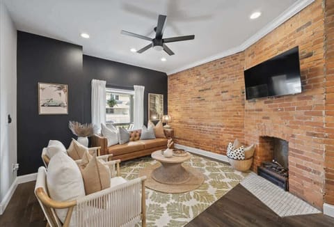 Stylish living room w/ exposed brick wall, cozy fireplace, TV, & comfy seating perfect for relaxing together