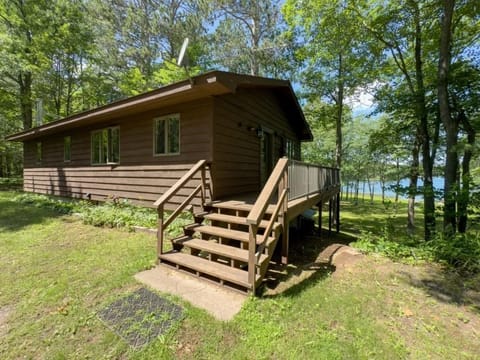 This cabin showcases a wooden exterior with a spacious deck that leads into a lush yard, perfect for outdoor activities.