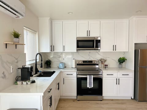 Full kitchen with electric stove, microwave, toaster, coffee maker, and more.