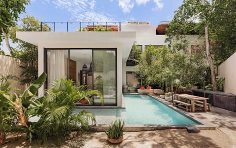 Glass entry with pool view — long private pool framed by tropical garden and linen curtains.