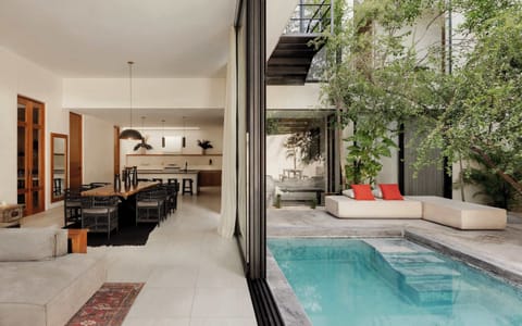 Open-plan interior with dark wood accents, kitchen, and pool access through glass doors.