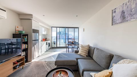 Sun-drenched living room with a cozy sectional and open balcony views.