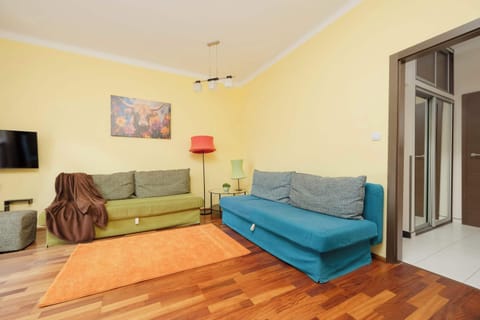 A cozy living room with a turquoise sofa, colorful wall art, and wooden flooring.