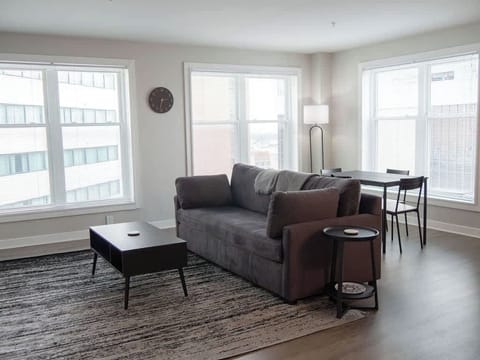 - Bright living room with large windows and comfy seating
- Downtown apartment stay with natural light views
- Relaxing open layout perfect for longer stays