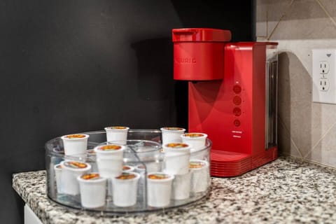 Convenient coffee station featuring a vibrant red Keurig machine and a selection of K-cups for your morning brew. Perfect for coffee lovers looking to start their day with ease and comfort during their stay.