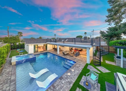 Twilight transforms this backyard into a private oasis with glowing pool lights, a spa, and sleek modern finishes—perfect for a luxurious evening dip or fireside chats.