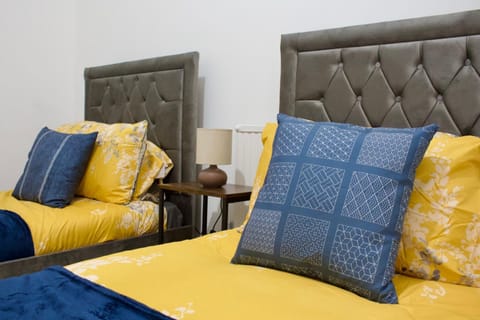 This bright bedroom features two single beds that offer both comfort and style, complete with hangers for your convenience. Perfect for ensuring a restful night's sleep.